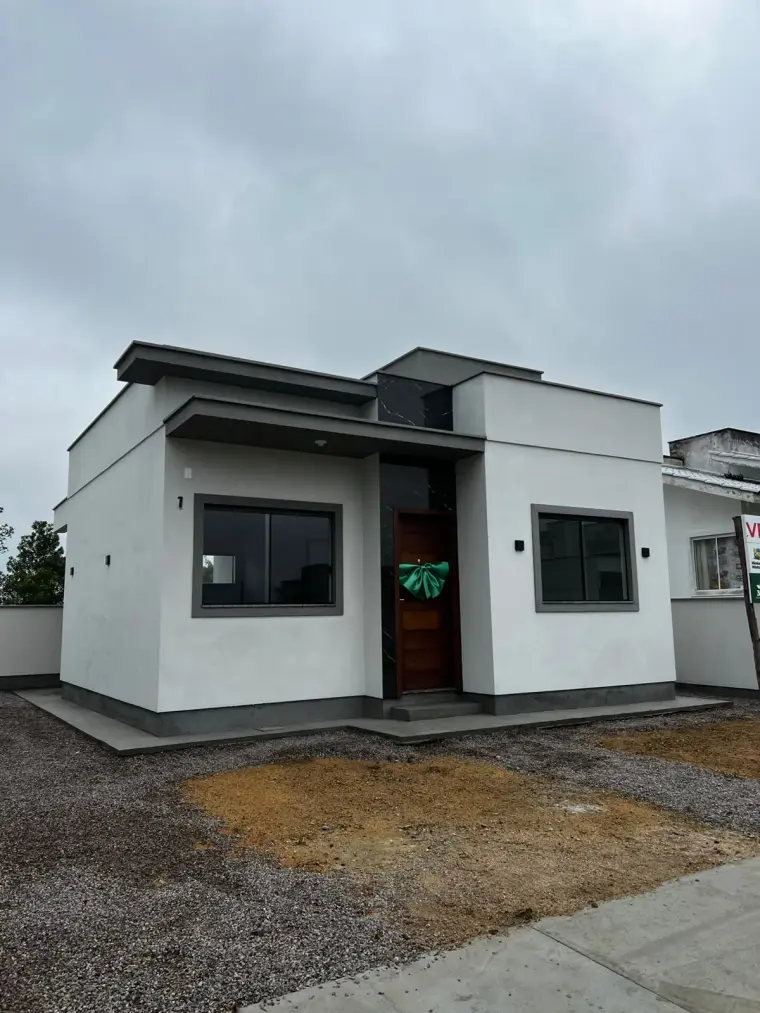 Fachada térrea branca da Casa Melissa, com detalhe em cinza.