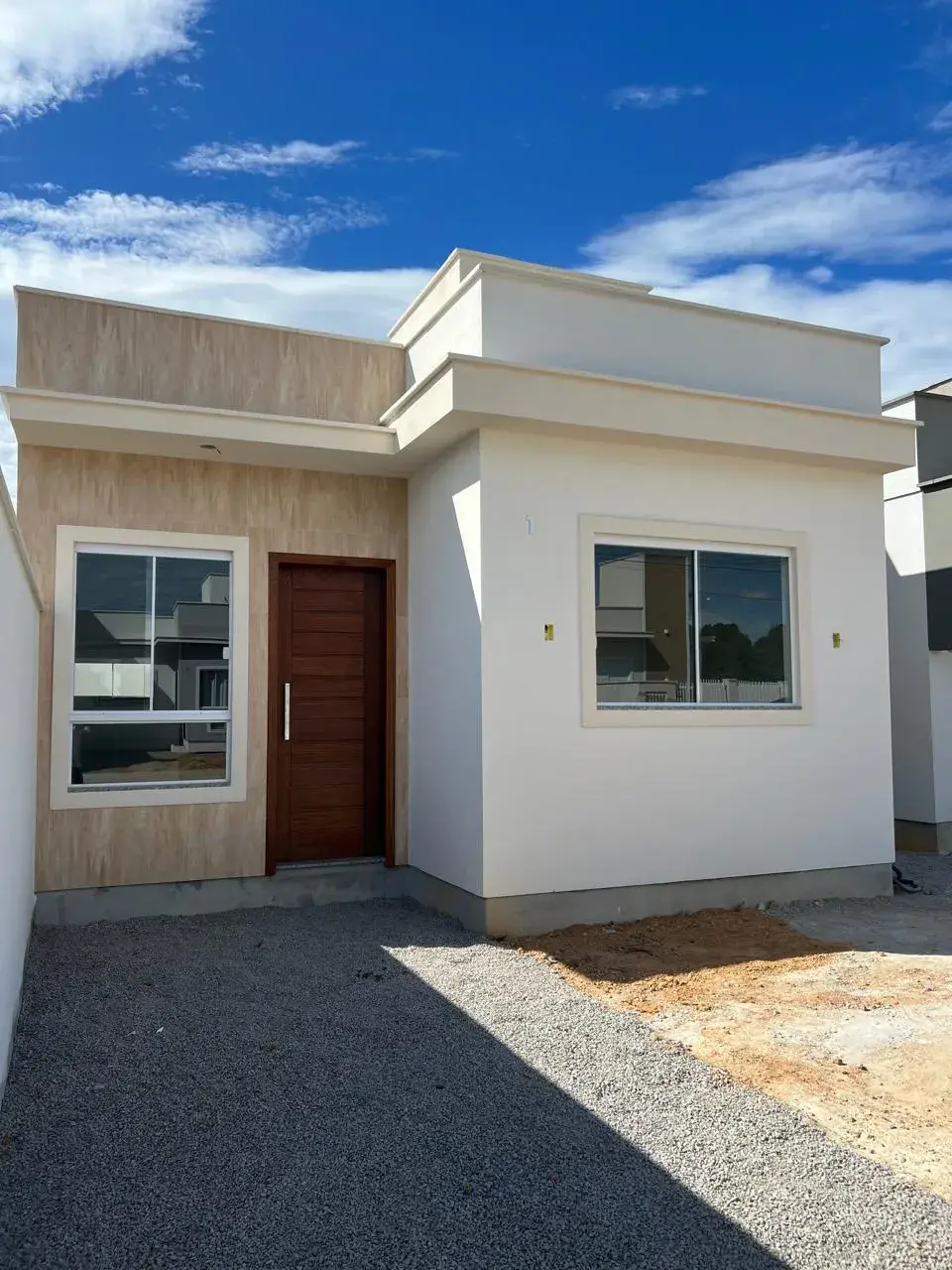 Casa Camélia, entregue pela 3 Lírios, com fachada clara, porta de madeira e céu azul.