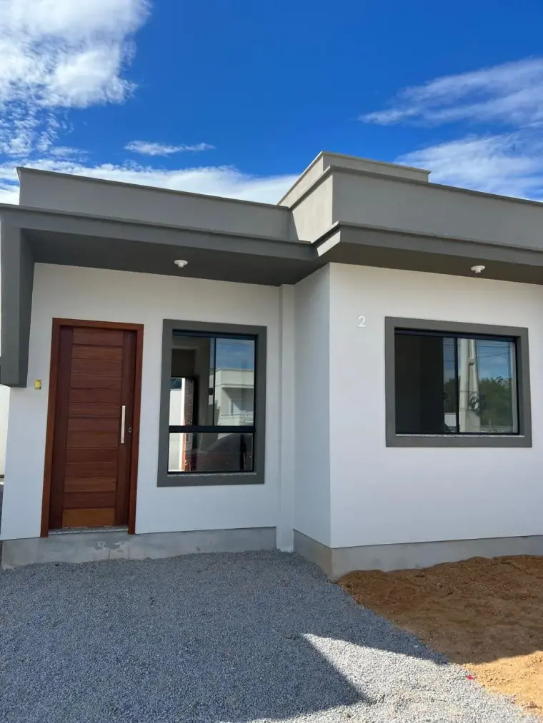 Fachada da Casa Rosa, branca, com platibanda cinza e porta de madeira.
